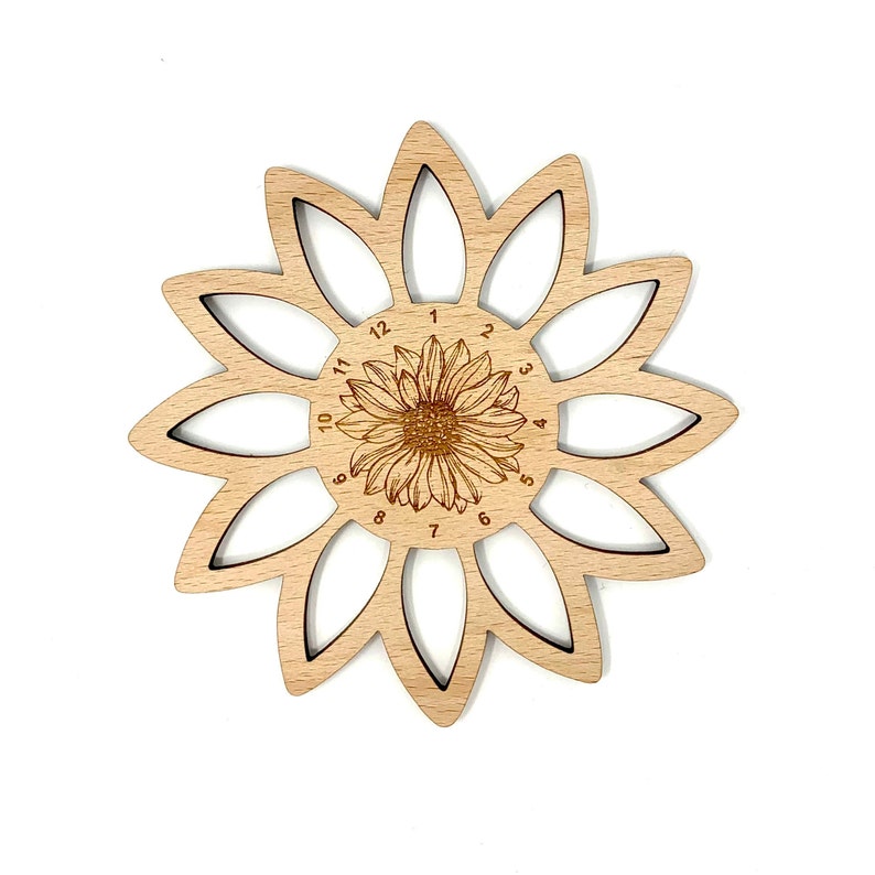 May include: A wooden sunflower-shaped yarn bowl with 12 slots for holding yarn. The bowl is made of light wood and has a sunflower design in the center with numbers 1 through 12 around the edge.