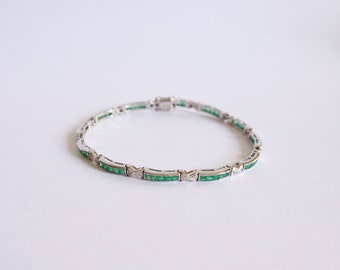 Line bracelet in 18 kt white gold setting emeralds and diamonds
