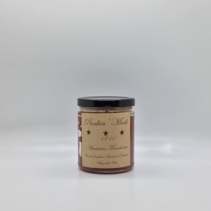 May include: A glass jar with a black lid filled with a red substance. The label reads "Pukin' Mash 1811 American Farmhouse" with three stars.