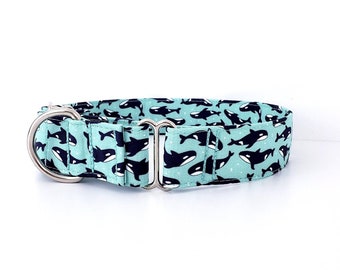 Puede incluir: Un collar para perro azul turquesa con un patrón repetido de ballenas orcas negras y blancas. El collar tiene una hebilla de metal plateado.