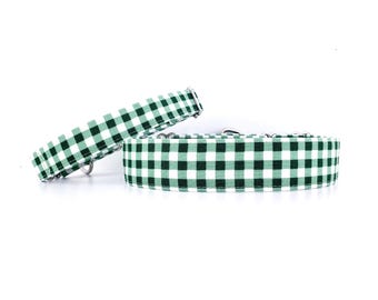 May include: Two green and white gingham dog collars with silver hardware. The collars are made of a sturdy fabric and are designed for comfort and durability.
