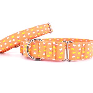 Puede incluir: Dos collares de perro naranja con un patrón de corazón blanco y amarillo. Los collares tienen hebillas de metal plateado.