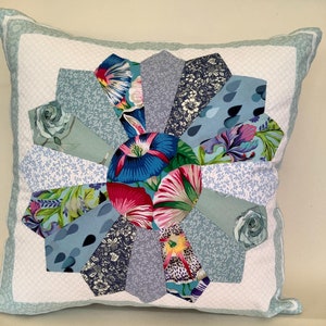 May include: A decorative cushion with a blue, green and white floral pattern. The cushion is made of fabric and has a square shape.