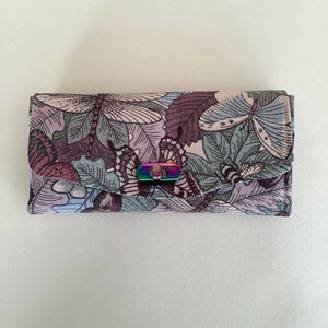 May include: A purple and blue wallet with a butterfly print and a rainbow-coloured metal clasp.