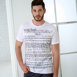 May include: A white t-shirt with the text "We the People" and the full text of the United States Constitution printed on the front.