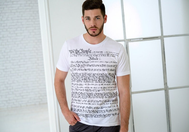 May include: A white t-shirt with the text "We the People" and the full text of the United States Constitution printed on the front.