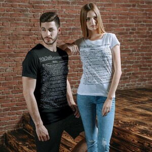 May include: Two people wearing black and white t-shirts with text printed on them. The text on the shirts is a document, possibly the US Constitution. The people are standing in front of a brick wall.