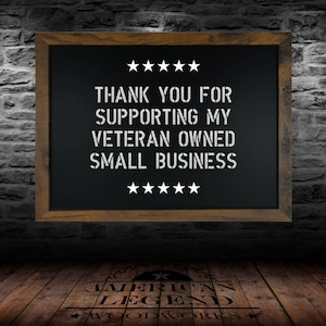 May include: A black chalkboard with a wooden frame hangs on a brick wall. The chalkboard has white text that reads "Thank you for supporting my veteran owned small business." There are five stars above and below the text.