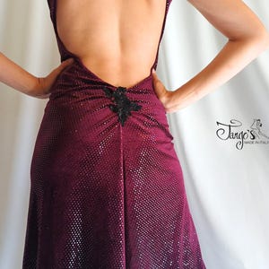 以下が含まれることがあります： ホルターネックと背中が大きく開いた、バーガンディ色のドレス。背中下部には黒い装飾が施されています。ドレスには控えめな水玉模様があり、「Tango's made in Italy」の文字があります。