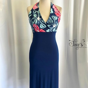 Puede incluir: Un vestido azul marino de tirantes con un corpiño de estampado floral. El corpiño es una mezcla de flores rosas, azules y blancas. El vestido tiene una silueta ajustada y un dobladillo ligeramente acampanado.