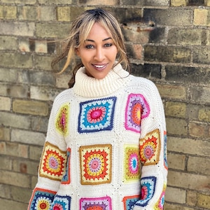 May include: Cream-coloured, hand-crocheted sweater with colourful square patterns. The sweater has a turtleneck and long sleeves with ribbed cuffs. The squares are in various colours, including pink, blue, yellow, and orange, creating a vibrant, patchwork design.