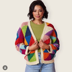 Op de afbeelding: Een kleurrijk gebreid vest met een geometrisch patroon in tinten rood, oranje, geel, groen, blauw, paars en roze. Het vest heeft een witte gebreide rand en een V-hals.