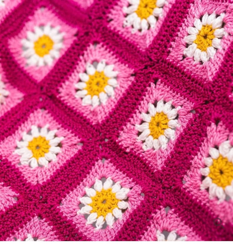 May include: A pink and white crocheted blanket with a daisy pattern.