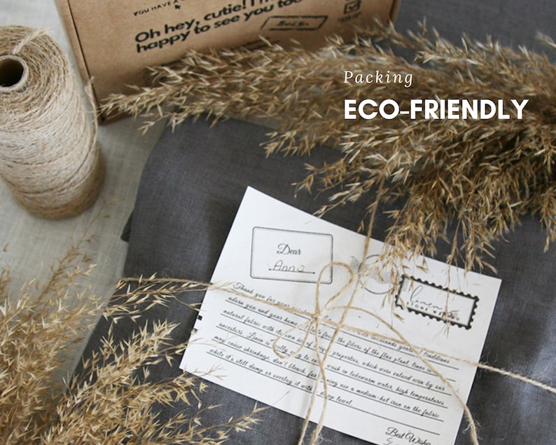 May include: A gray linen fabric package tied with twine and a handwritten note that says "Dear Anna" and "Best Wishes". The package is surrounded by dried grass and the text "Packing ECO-FRIENDLY" is visible in the background.