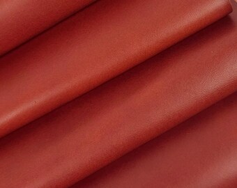 May include: A stack of four red leather sheets. The leather is smooth and has a slight sheen.