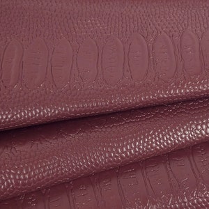 Peut inclure: Cuir synthétique bordeaux avec un motif de crocodile en relief. Le cuir est plié en trois.