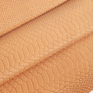 May include: A close-up of a brown faux leather fabric with a snakeskin pattern.