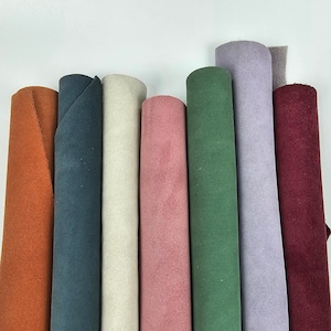 May include: Eight rolls of suede fabric in various colors, including orange, teal, beige, pink, green, lavender, and burgundy.