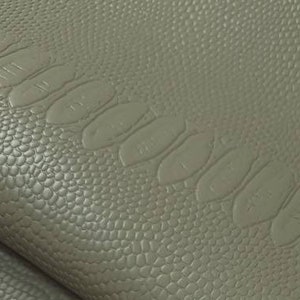 Könnte beinhalten: Nahaufnahme eines strukturierten, grünen Kunstleders mit Krokodil-Muster.