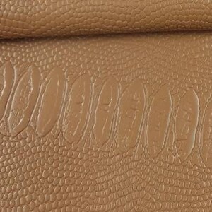 Könnte beinhalten: Nahaufnahme eines braunen Kunstleders mit einer strukturierten Alligator-Haut-Muster.