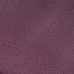 Op de afbeelding: Een close-up van een stuk bordeauxrood leer met een krokodil-reliëfpatroon.