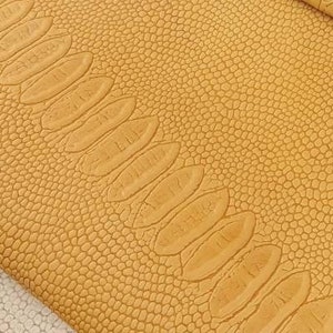 Puede incluir: Primer plano de una tela texturizada de color amarillo con un patrón de piel de cocodrilo.