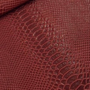 May include: Close-up of a burgundy faux snakeskin fabric with a textured pattern.