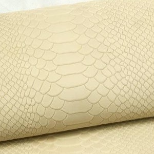 May include: Cream-coloured faux leather fabric with a snakeskin embossed pattern.