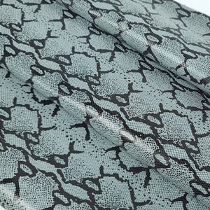 May include: A close-up of a grey and black snakeskin fabric with a textured pattern.