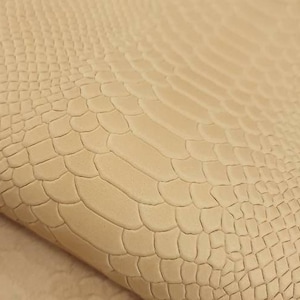 Op de afbeelding: Close-up van een beige lederen stof met een textuur van een alligatorhuid.