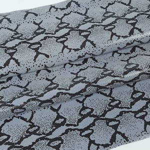 Może przedstawiać: Szary materiał z czarnym wzorem skóry węża.