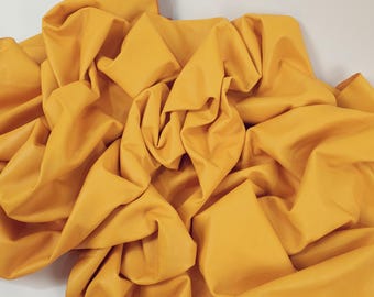 May include: A crumpled piece of yellow leather fabric. The fabric is soft and has a smooth texture.