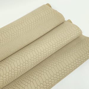 May include: Beige faux leather with a snakeskin embossed pattern. The leather is folded in thirds, showing the texture from different angles.