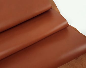 May include: Close-up of a stack of brown leather sheets. The leather has a smooth, polished finish.