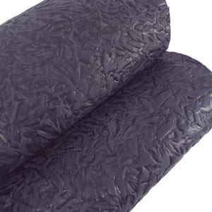 May include: Two rolls of dark gray textured fabric. The fabric has a raised, crinkled pattern, creating a unique, tactile surface. The material appears to be flexible and suitable for various craft and design projects.