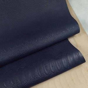 May include: Two pieces of dark blue faux leather with a textured, embossed pattern resembling scales.