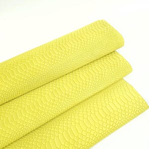 Può includere: Primo piano di tre pezzi di pelle sintetica gialla con motivo a pelle di serpente. La pelle è piegata in tre parti, con la parte superiore piegata sulla parte centrale, e la parte centrale piegata sulla parte inferiore.