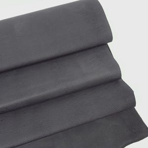 May include: A close-up of a dark gray textured fabric folded in thirds. The fabric has a subtle, embossed pattern.