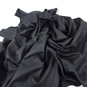 Può includere: Un pezzo di pelle nera, piegato e stropicciato, con il testo "Leatherforcraft" nell'angolo in basso a sinistra.