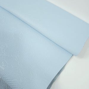 Könnte beinhalten: Ein hellblauer Kunstlederstoff mit einer Schlangenhautprägung.