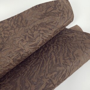 May include: Two sheets of brown, textured paper with a crinkled, leaf-like pattern. The paper has a rough, uneven edge and a matte finish. The color is a warm, earthy brown, with darker shading in the creases.