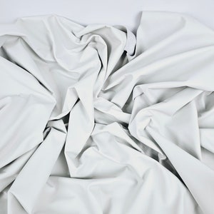 May include: White leather fabric with a wrinkled texture. The fabric is folded and draped in a way that creates a soft, flowing look.