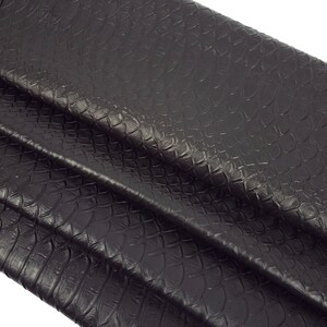 Könnte beinhalten: Nahaufnahme eines dunkelbraunen, strukturierten Stoffes mit Schlangenhautmuster.