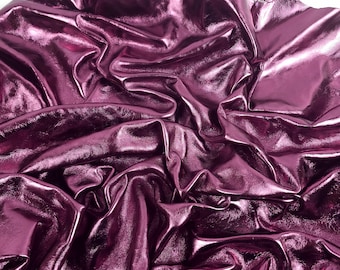 May include: A sheet of shiny, metallic magenta leather. The material is crumpled and folded, creating shadows and highlights across its surface. The leather has a smooth, reflective finish, giving it a luxurious appearance.