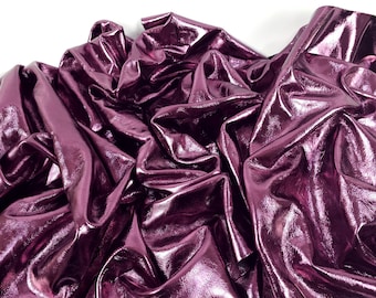 May include: A close-up of a deep purple metallic leather fabric. The fabric is wrinkled and has a shiny, reflective surface.