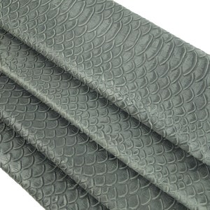 Puede incluir: Tela de imitación de cuero gris con un patrón texturizado de piel de serpiente.