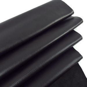 May include: Black leather fabric folded in layers. The leather has a textured surface.