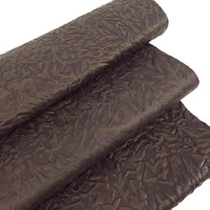 May include: Close-up of a textured, dark brown fabric with a crinkled appearance. The material is folded and rolled, revealing the intricate surface details. The fabric has a matte finish and a rich, earthy tone, suitable for various craft projects.