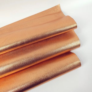 May include: A folded piece of rose gold leather with a textured surface.