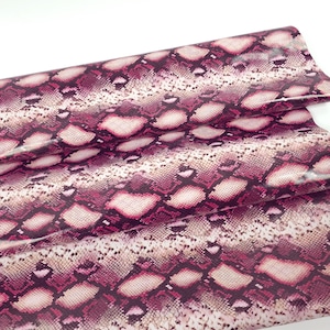 Op de afbeelding: Roze en bruine stof met een slangenhuidpatroon en een glanzende afwerking.